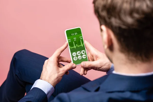 Cropped view of businessman using smartphone with health app, isolated on pink — Stock Photo