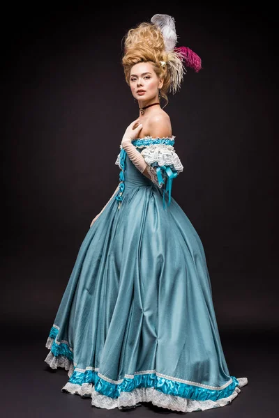 Attractive victorian woman in wig standing in blue dress on black — Stock Photo