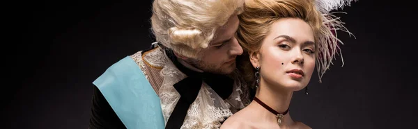 Panoramic shot of handsome victorian man looking at woman in wig on black — Stock Photo