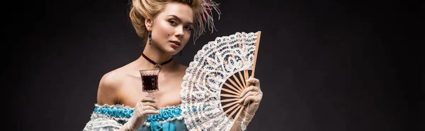 Panoramic shot of victorian woman holding fan and wine glass on black — Stock Photo