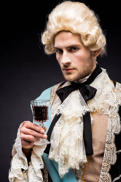 Pompous victorian man in wig holding wine glass on black — Stock Photo