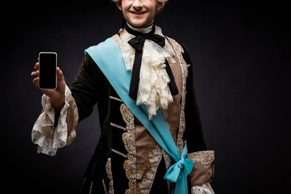 Cropped view of happy victorian man holding smartphone with blank screen on black — Stock Photo