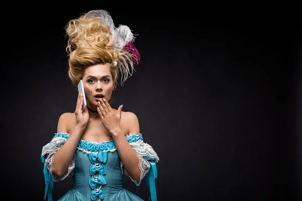 Sorprendida joven victoriana hablando en el teléfono inteligente en negro - foto de stock