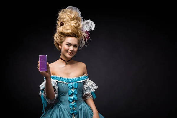 KYIV, UKRAINE - JUNE 5, 2019: attractive victorian woman holding smartphone with instagram app on screen on black — Stock Photo