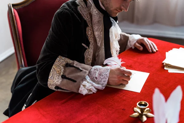 Cropped view of victorian man holding feather and writing letter — Stock Photo