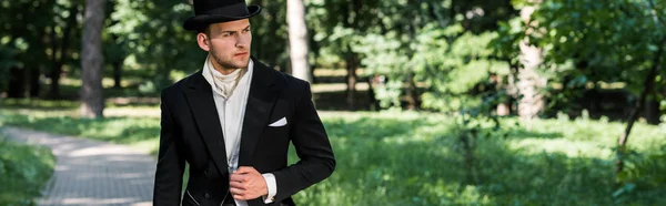 Panoramic shot of handsome victorian man in hat standing outside — Stock Photo