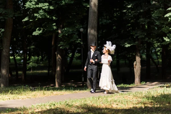 Cheerful victorian man and woman in hats walking outside — Stock Photo