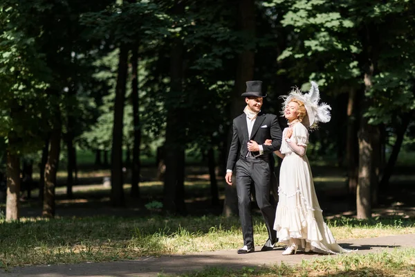 Happy young victorian woman and handsome man in hat walking outside — Stock Photo