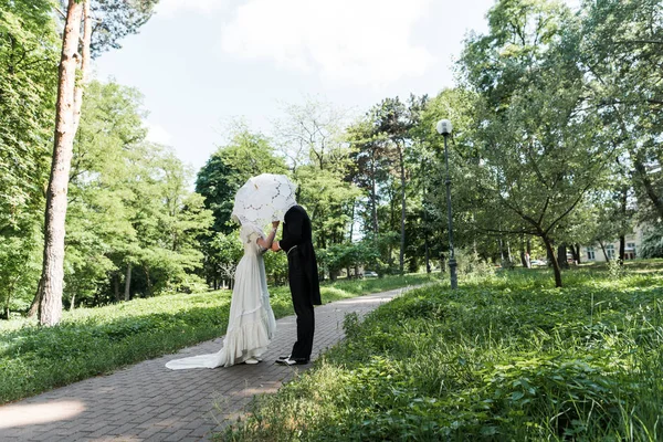 Victorienne homme et femme couvrant les visages tout en tenant parapluie — Photo de stock