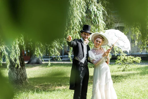 Selective focus of aristocratic man pointing with finger near woman holding umbrella — Stock Photo