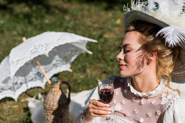 Messa a fuoco selettiva di attraente giovane donna vittoriana con gli occhi chiusi in possesso di bicchiere di vino — Foto stock
