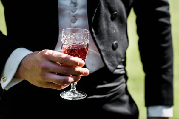 Cropped view of victorian man in suit holding wine glass with drink — Stock Photo