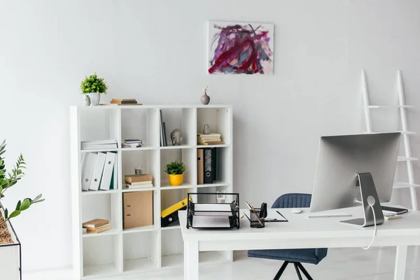 Weißes Zimmer mit Wandmalerei, Bücherregal, Blumentöpfen mit Pflanzen und Tisch mit Computer, Dokumententablett und Bleistiftkasten — Stockfoto