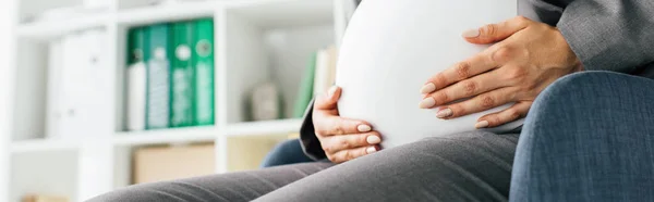 Panoramaaufnahme einer schwangeren Frau mit Bauch im Bürostuhl — Stockfoto