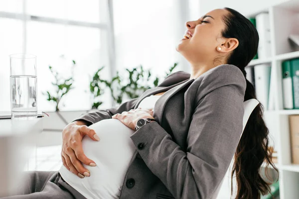 Pregnant woman holding belly, screaming and enduring pain — Stock Photo