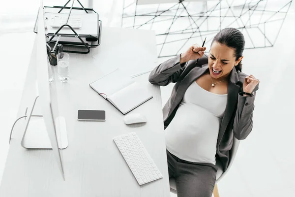 Pregnant woman sitting behind table and screaming because of pain — Stock Photo