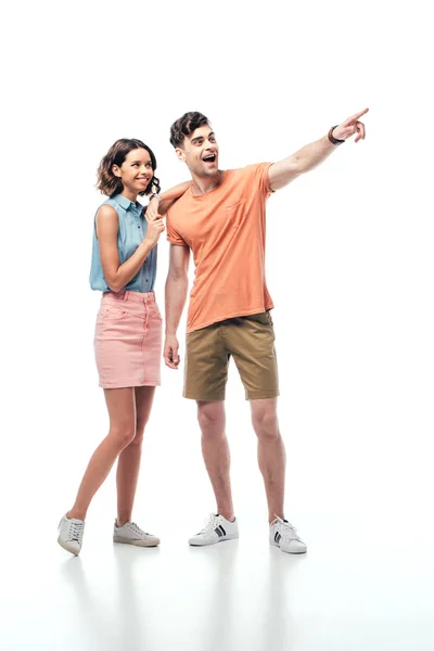 Возбужденный мужчина смотрит в сторону и указывает пальцем на веселую женщину на белом фоне — стоковое фото