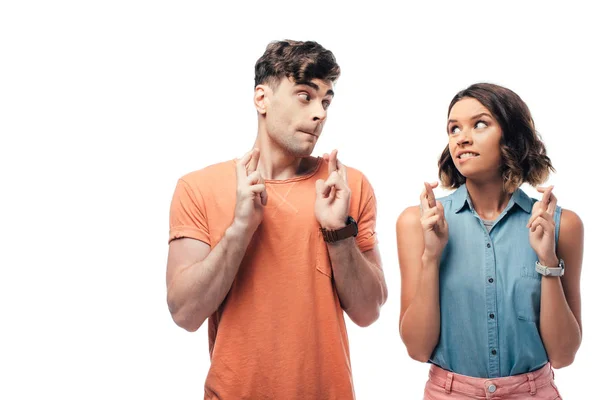 Esperando homem e mulher segurando dedos cruzados e olhando um para o outro isolado no branco — Fotografia de Stock