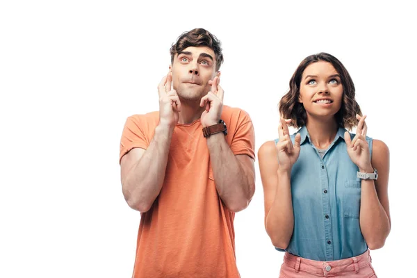Joven hombre y mujer mirando hacia arriba mientras sostiene los dedos cruzados aislados en blanco - foto de stock