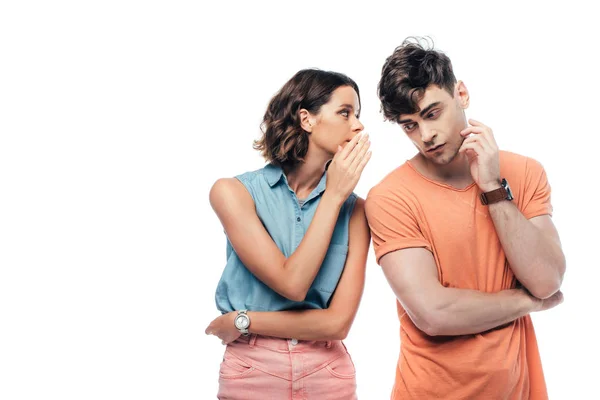 Atractiva mujer joven susurrando al hombre reflexivo aislado en blanco - foto de stock