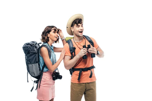 Two excited young tourists with binoculars and digital camera looking away isolated on white — Stock Photo