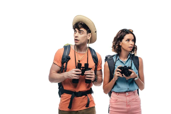 Two thoughtful young tourists with digital camera and binoculars looking away isolated on white — Stock Photo