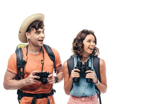 Two excited young tourists with digital camera and binoculars looking away isolated on white — Stock Photo