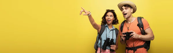 Panoramaaufnahme zweier aufgeregter Touristen, die auf gelbem Hintergrund wegschauen — Stockfoto