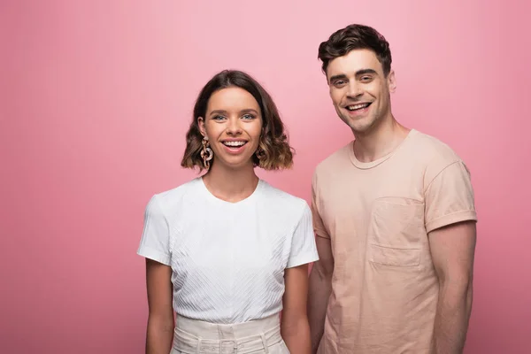Jeune, gai homme et femme regardant la caméra sur fond rose — Photo de stock