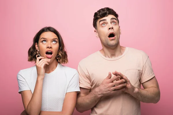 Schockierter Mann und Wooman blickt auf rosa Hintergrund auf und gestikuliert — Stockfoto