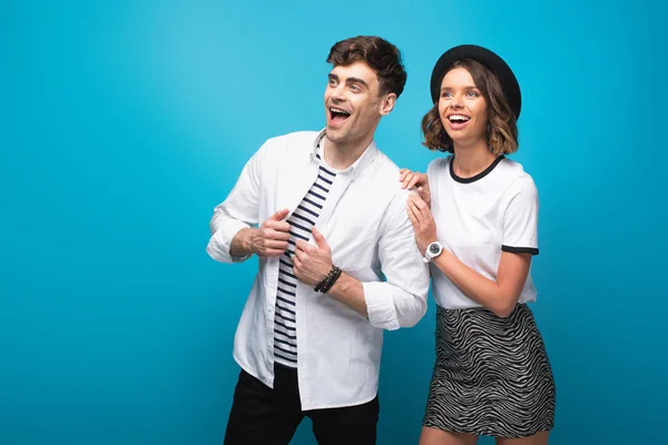 Jeune, homme et femme à la mode souriant et regardant loin sur fond bleu — Photo de stock