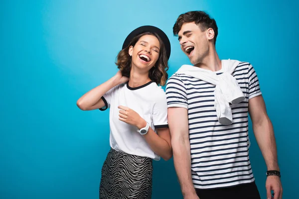 Счастливые, трогательные мужчина и женщина, смеющиеся вместе на голубом фоне — стоковое фото