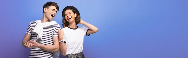 Colpo panoramico di giovane, allegra coppia ridere insieme su sfondo blu — Foto stock
