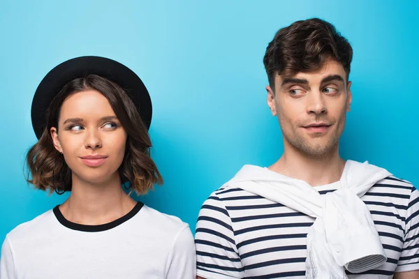 Young, positive man and woman looking at each other on blue background — Stock Photo