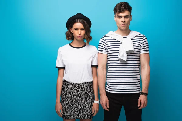 Displeased, trendy man and woman looking at camera on blue background — Stock Photo