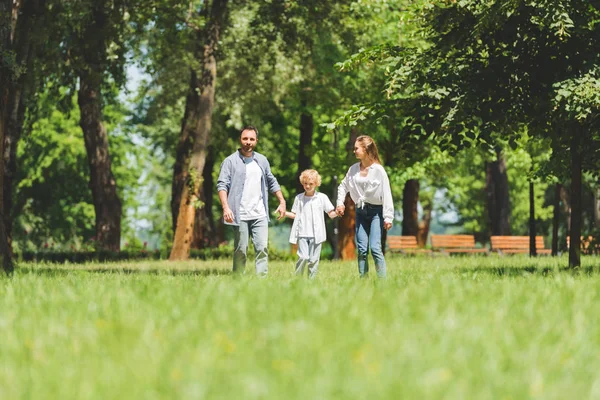 Focalizzazione selettiva della famiglia felice che si tiene per mano e corre nel parco durante il giorno — Foto stock