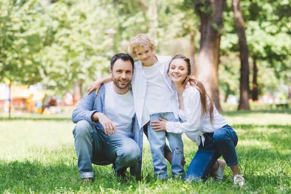 Glückliche Familie blickt in die Kamera und umarmt sich im Park — Stockfoto