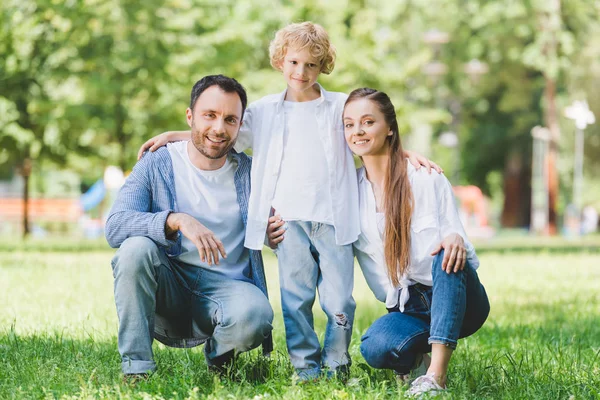 Famille heureuse regardant la caméra, posant et étreignant dans le parc — Photo de stock