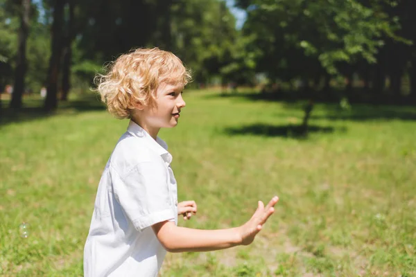 Adorable boy in white Gesturing in park with copy space — Stock Photo