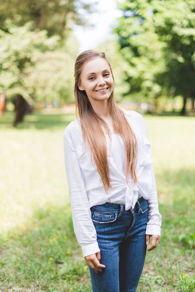 Foco seletivo da bela mulher sorridente no parque olhando para a câmera — Fotografia de Stock