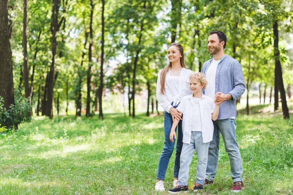 Famille heureuse tenant la main dans le parc avec espace de copie — Photo de stock