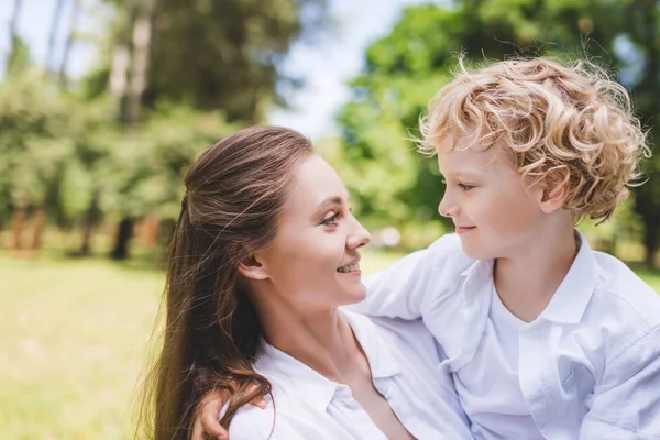 Beautiful happy mother looking at adorable son in park — Stock Photo