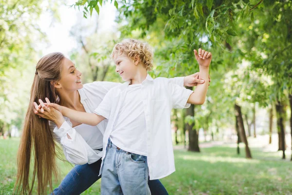 Красива щаслива мати тримає руки з чарівним сином в парку — стокове фото