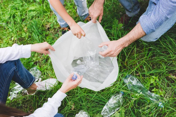 Top view of family putting garbage in plastic bag in park — Stock Photo