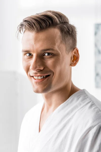 Smiling handsome masseur looking at camera in clinic — Stock Photo