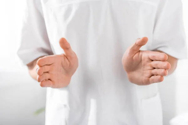 Cropped view of masseur gesturing at camera in clinic — Stock Photo