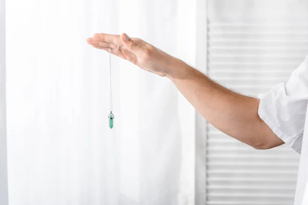 Cropped view of hypnotist holding green stone in clinic — Stock Photo