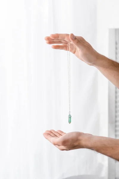 Cropped view of hypnotist holding green stone in clinic — Stock Photo