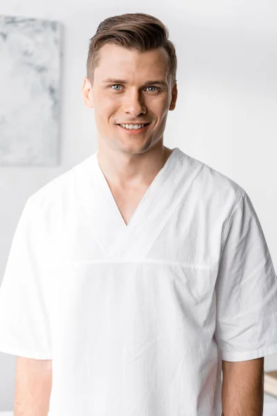 Front view of smiling masseur looking at camera in clinic — Stock Photo