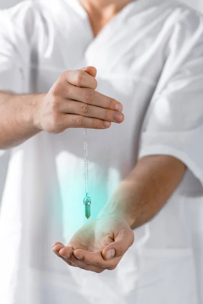 Cropped view of hypnotist holding green stone in clinic — Stock Photo